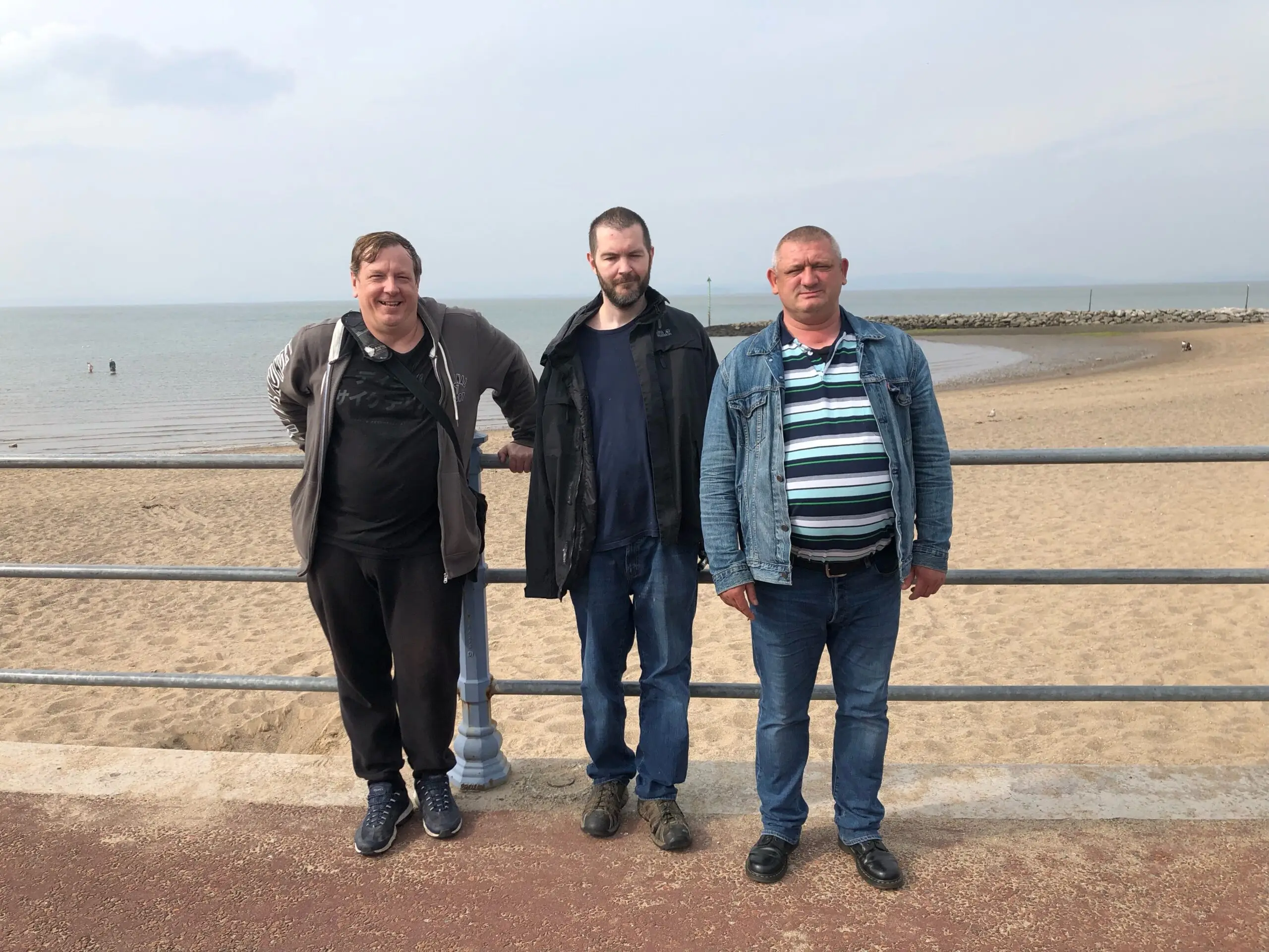 3 male residents on promenade in front of beach