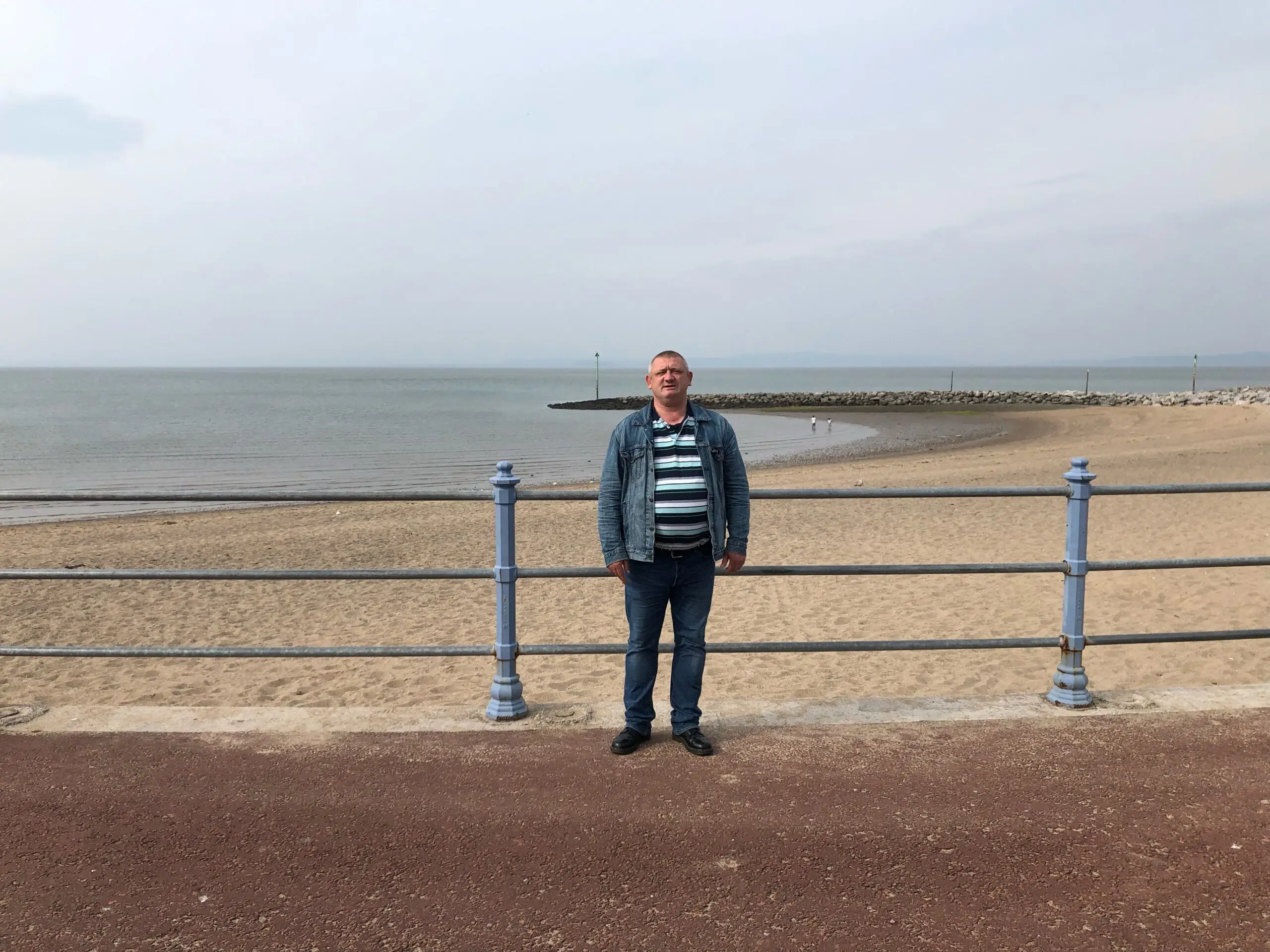 male resident in striped top on promenade in front of beach