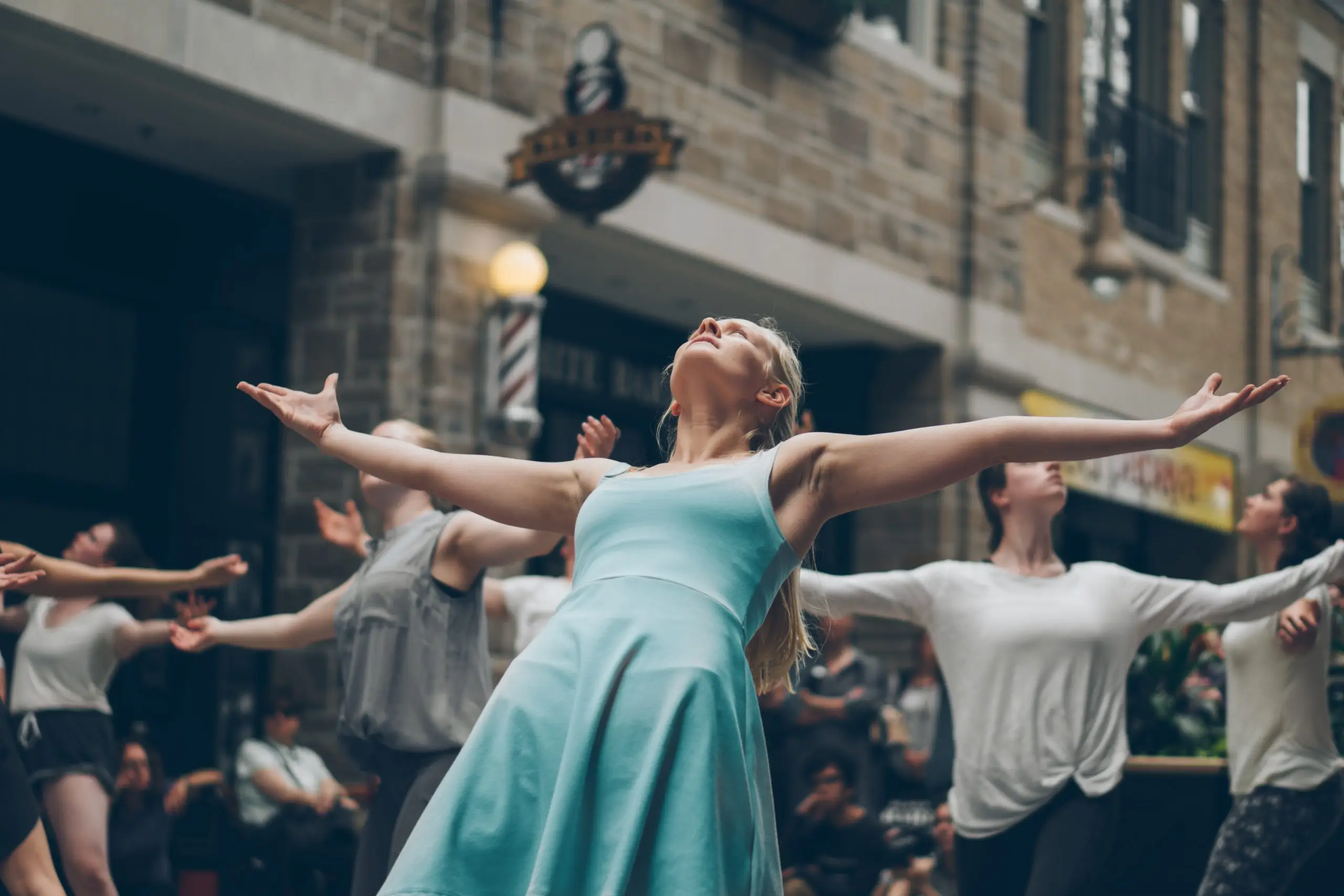 woman in blue dress with arms outstretched looking towards the sky