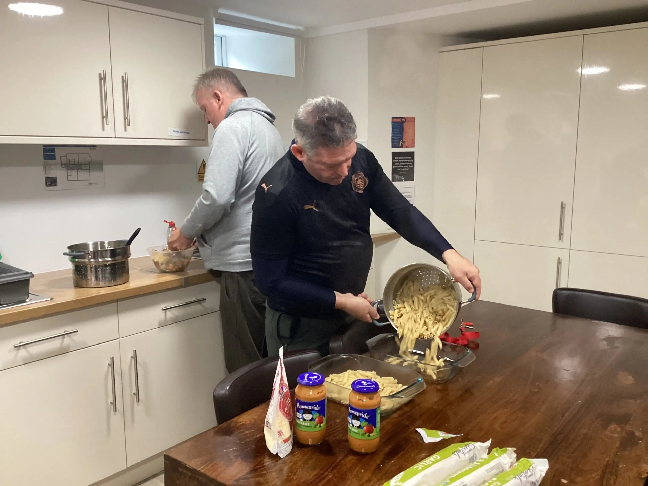 resident pouring pasta from pan into dish