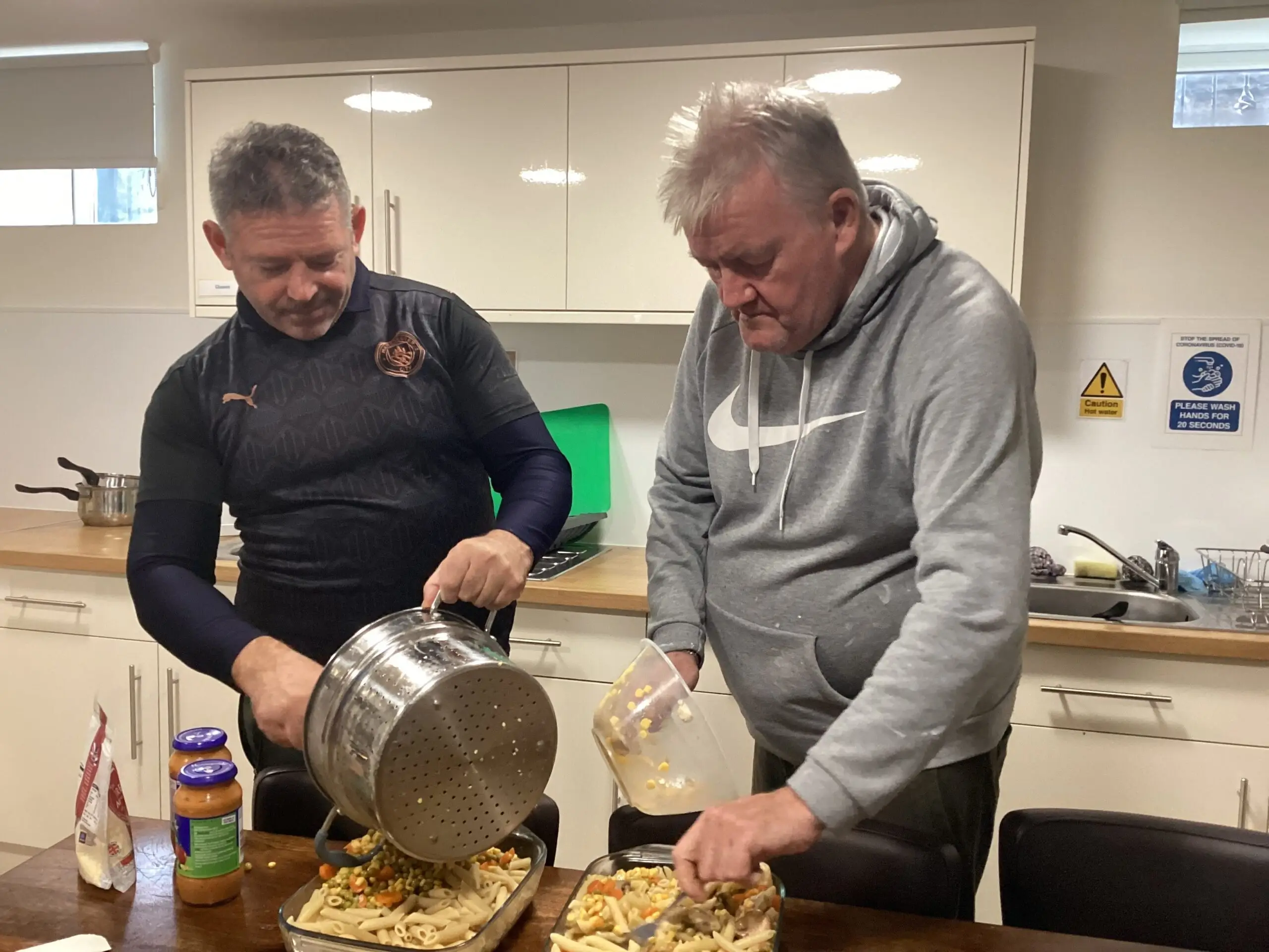 2 male residents preparing pasta dish