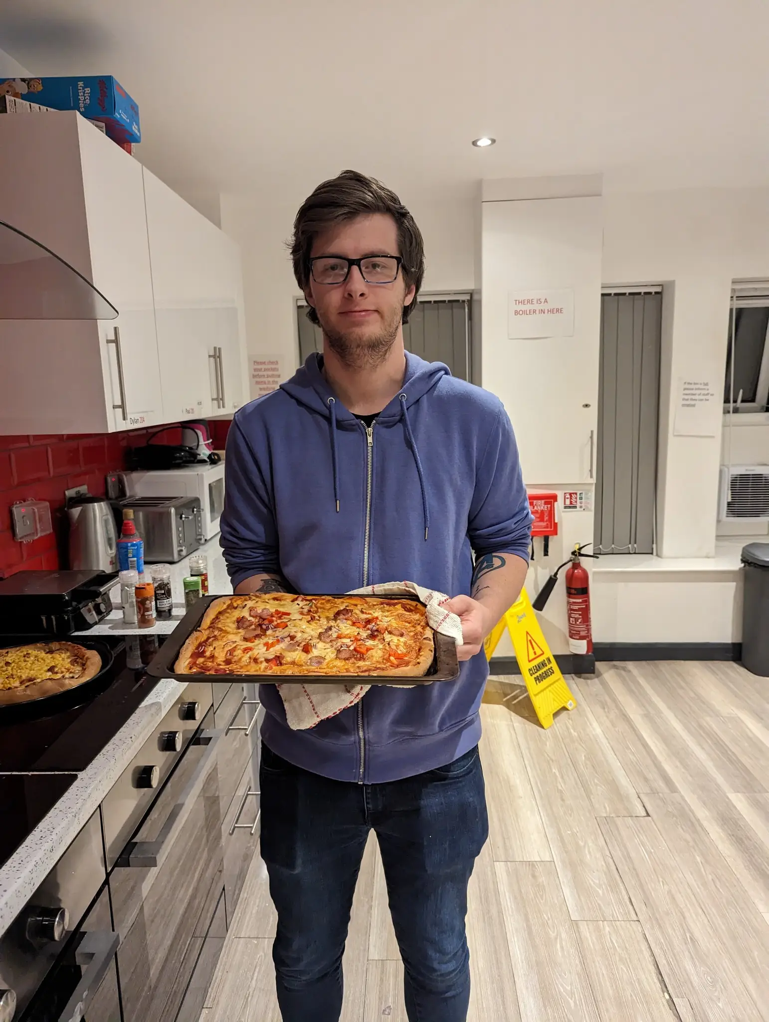 Male resident holding homemade pizza