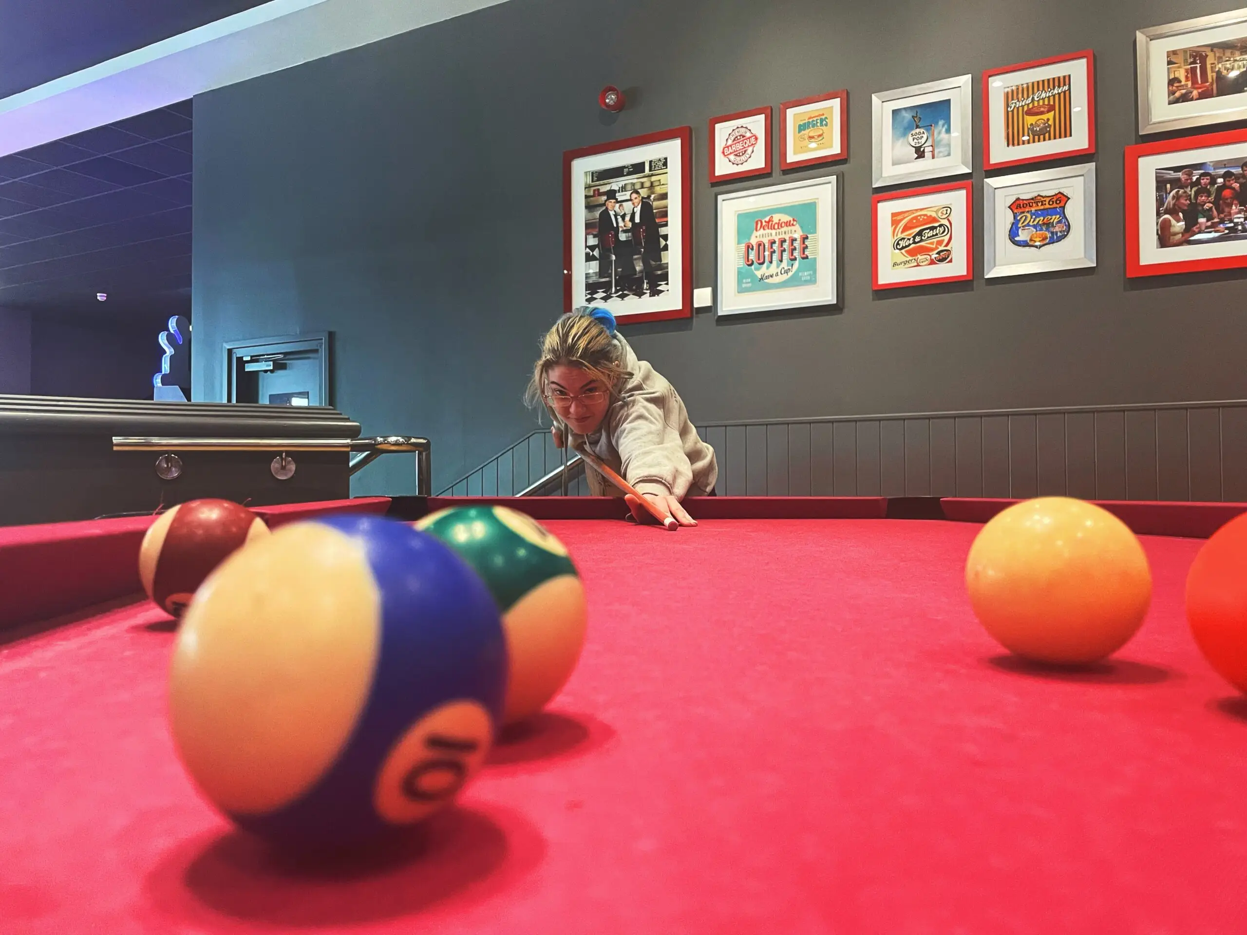female playing pool on red pool table