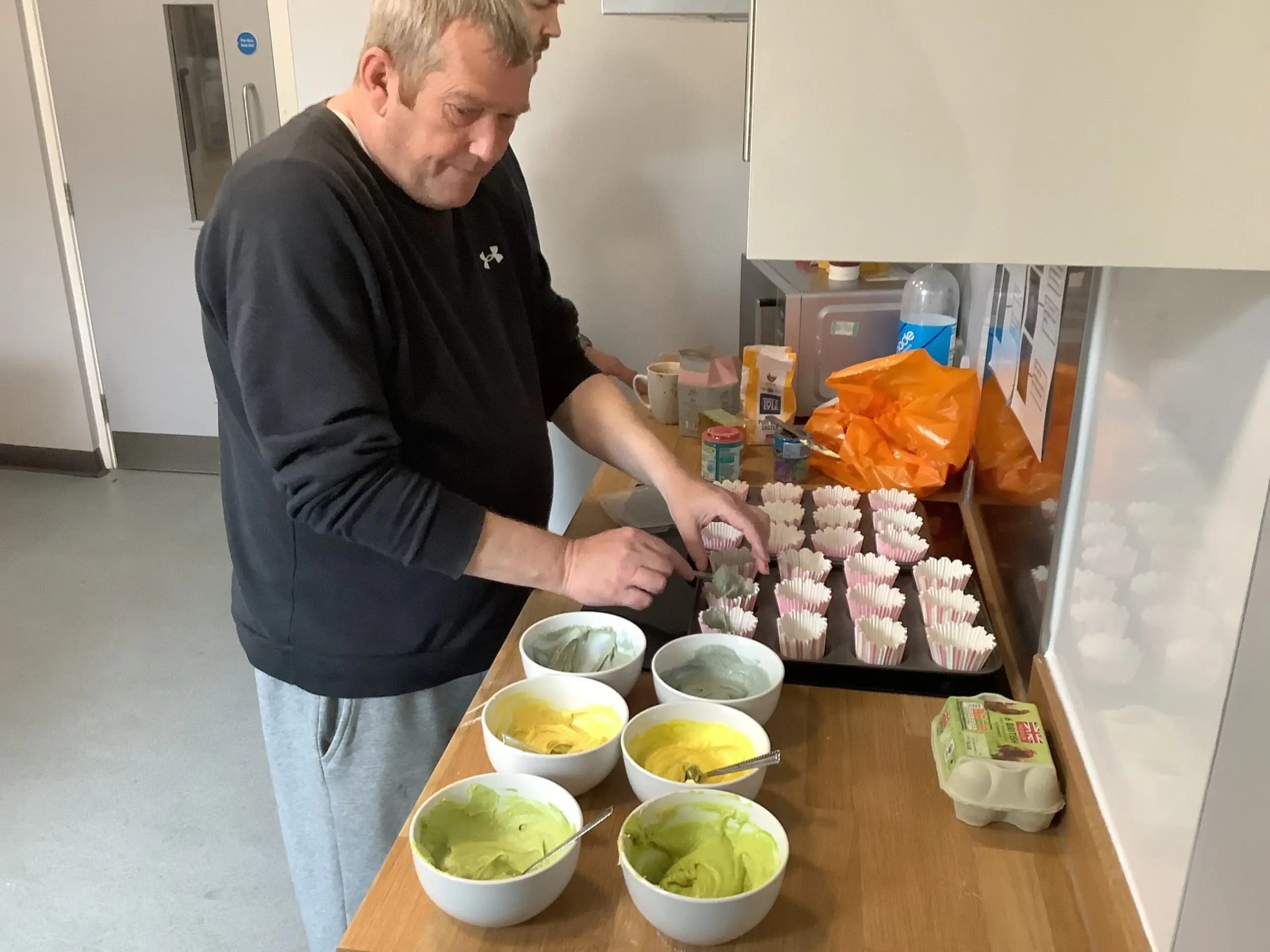 male adding cupcake batter to cupcake cases