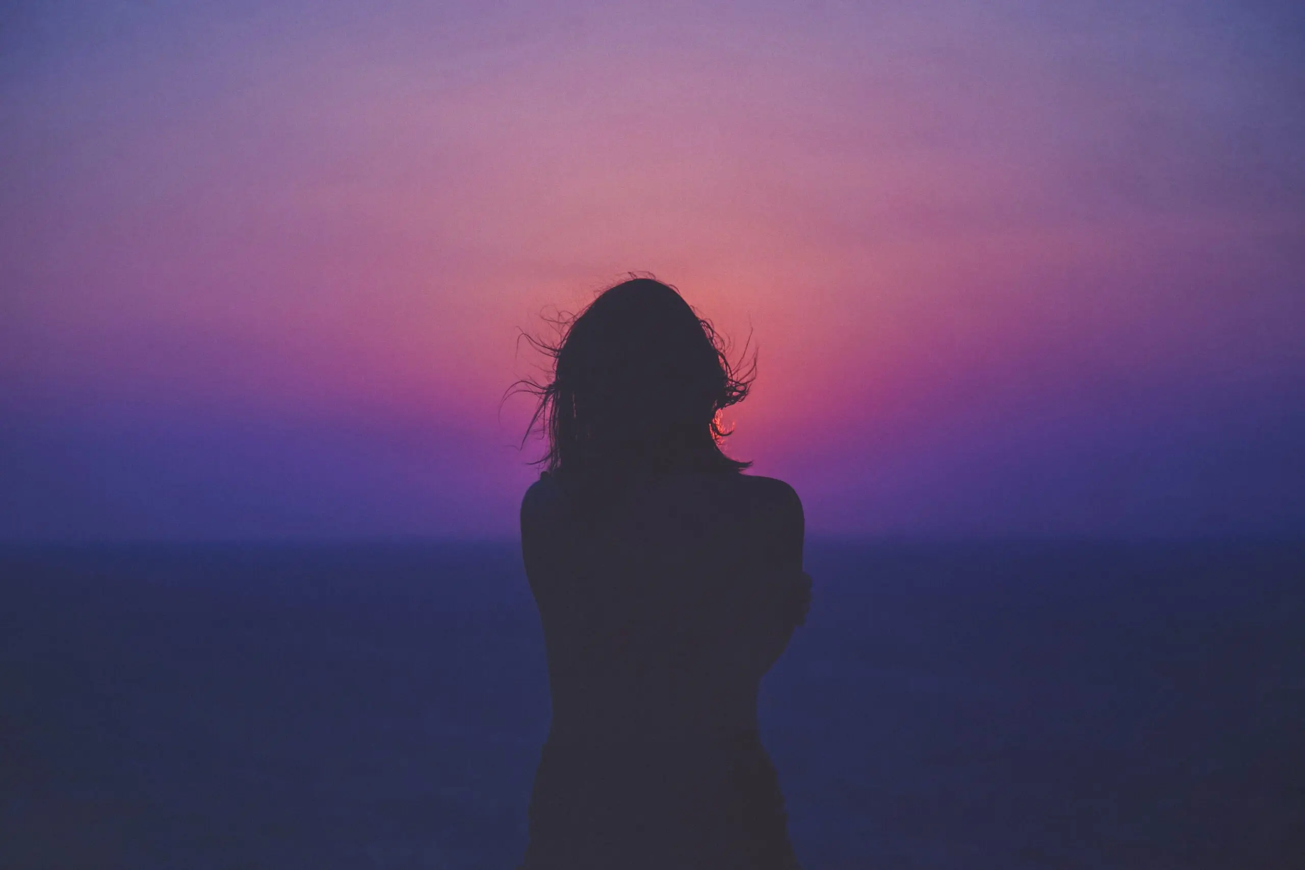 silhouette of a woman against an orange-purple background