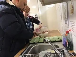 residents spooning cake mix into wrappers
