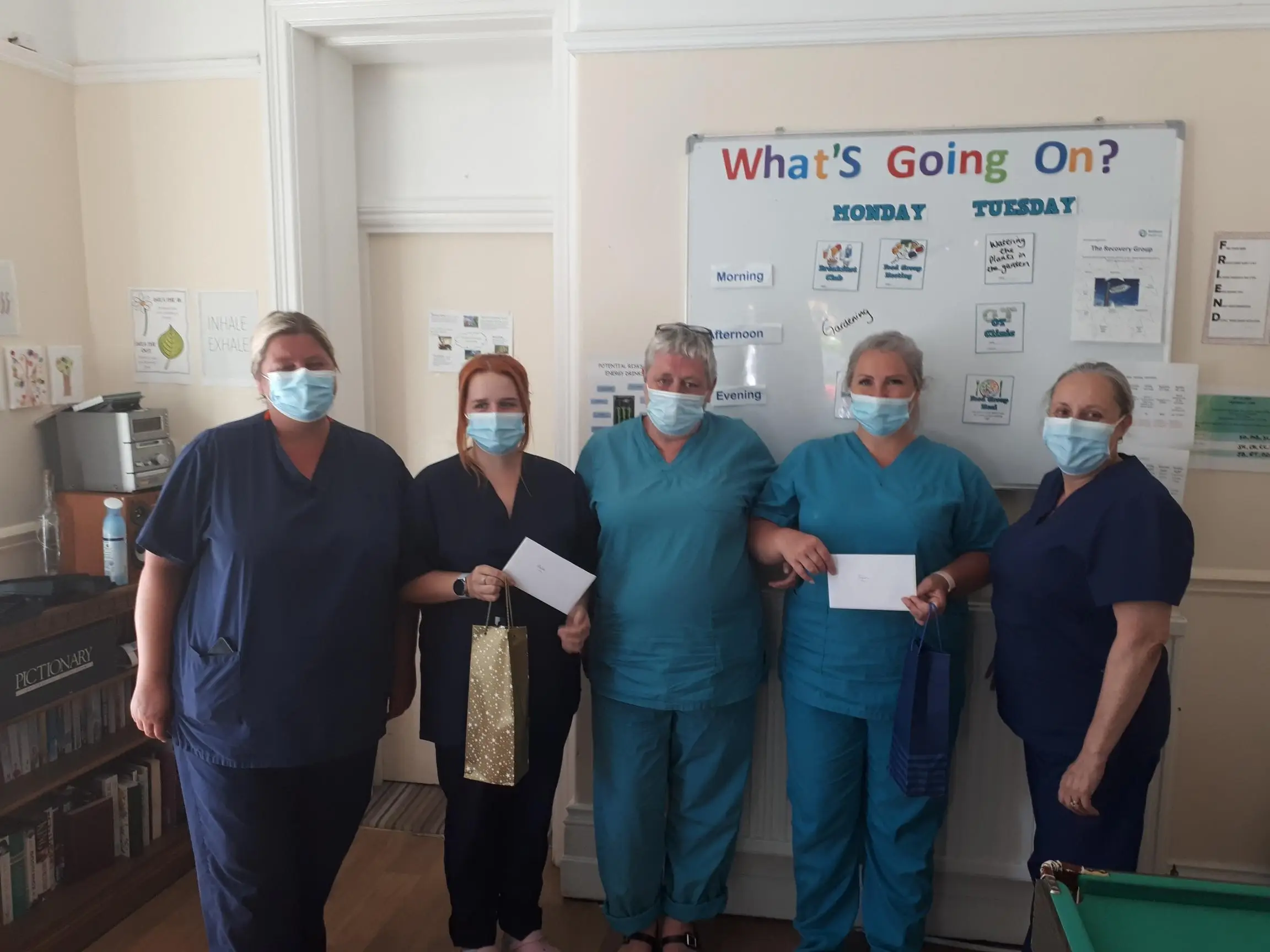 members of staff pose with their thank you cards